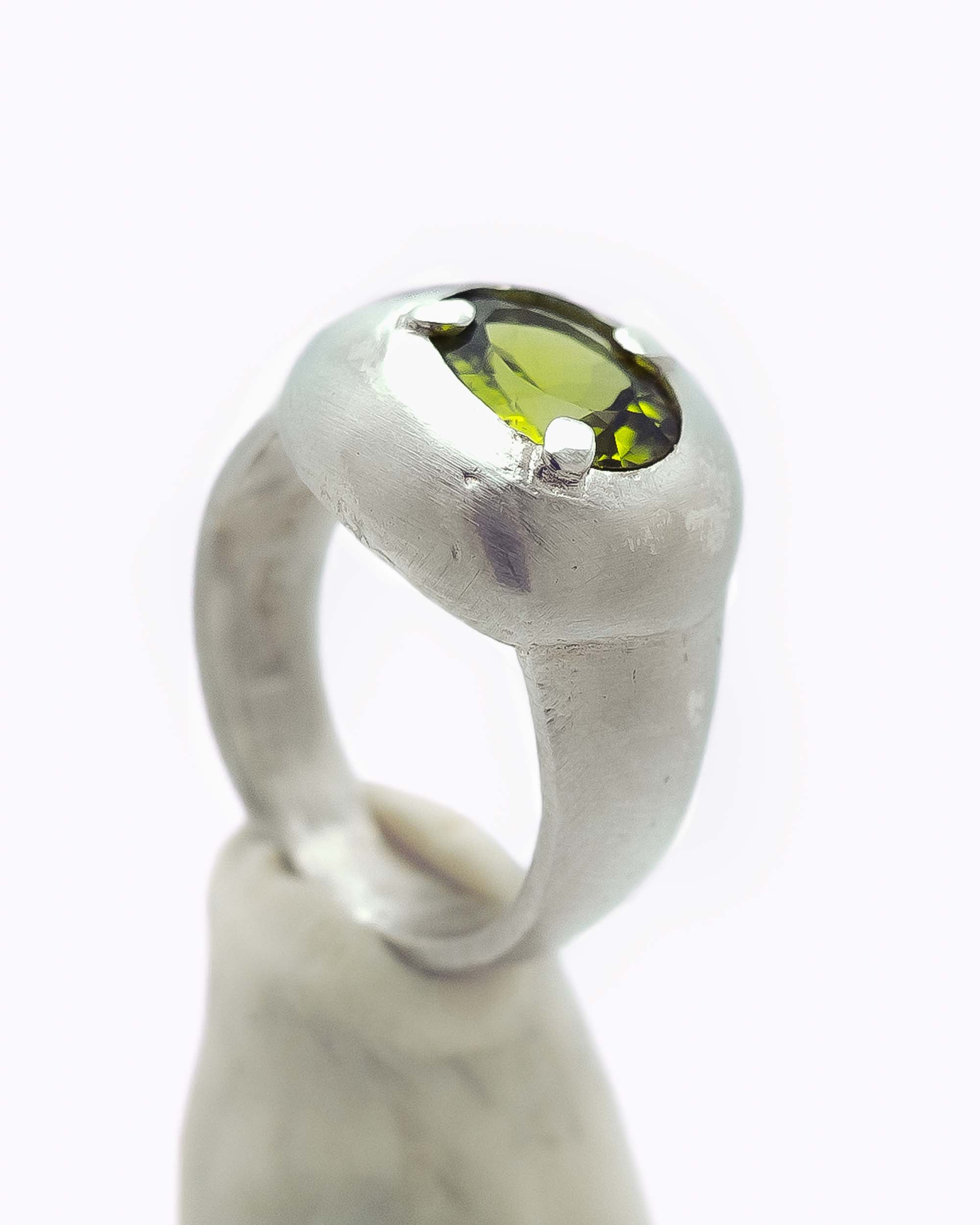 Silver shield shaped ring with a peridot stone in the center.